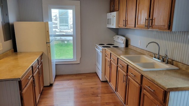 507 W Illinois St, Kirksville, MO 63501 - kitchen featuring white appliances, light wood-type flooring, a sink, brown cabinetry, and wallpapered walls