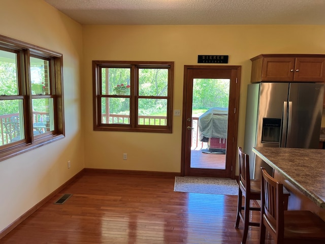 doorway with baseboards, a healthy amount of sunlight, visible vents, and dark wood-type flooring