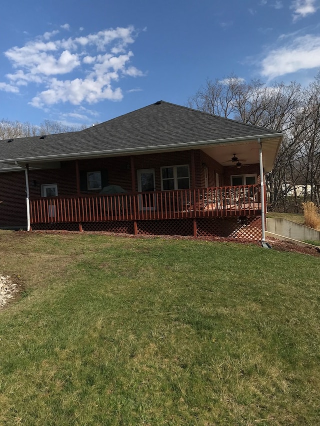 back of property with roof with shingles, a wooden deck, a lawn, and ceiling fan