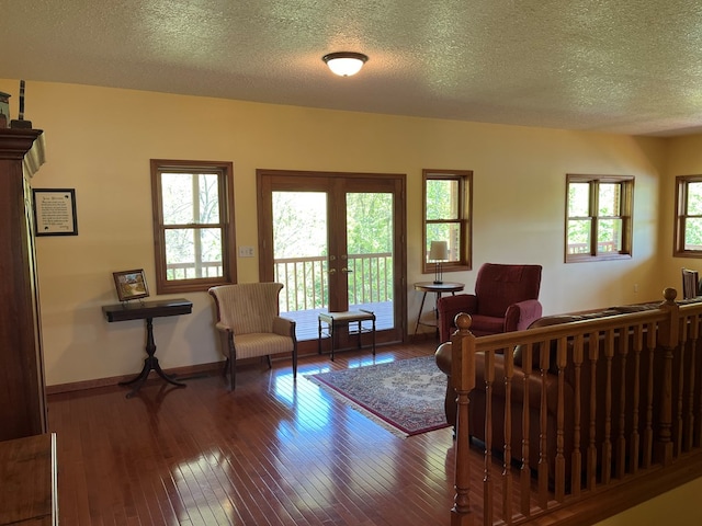 living room with a textured ceiling, a wealth of natural light, baseboards, and wood-type flooring