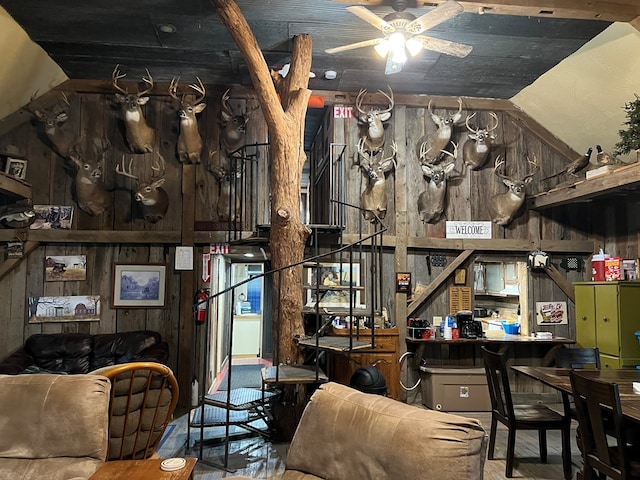 interior space with vaulted ceiling, ceiling fan, and wooden walls