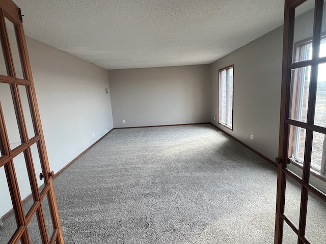 carpeted empty room featuring baseboards and a textured ceiling