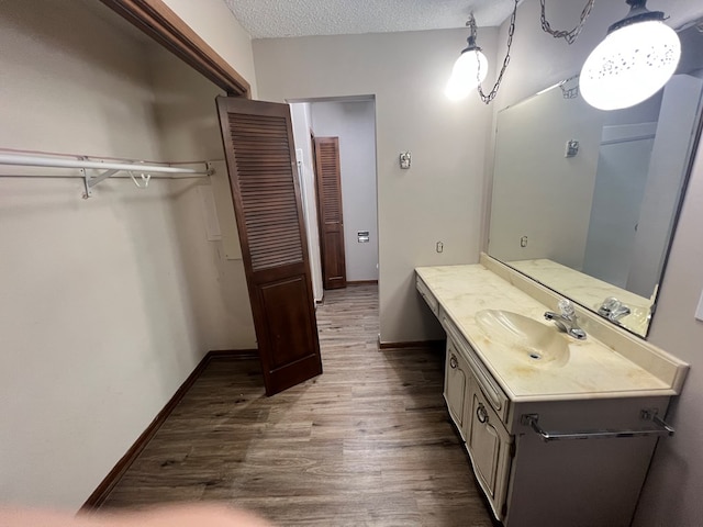 bathroom with a closet, a textured ceiling, vanity, wood finished floors, and baseboards