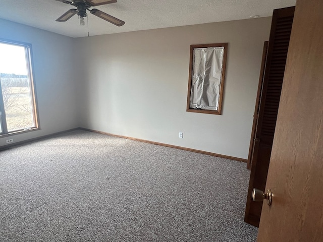 carpeted empty room featuring a textured ceiling, ceiling fan, and baseboards