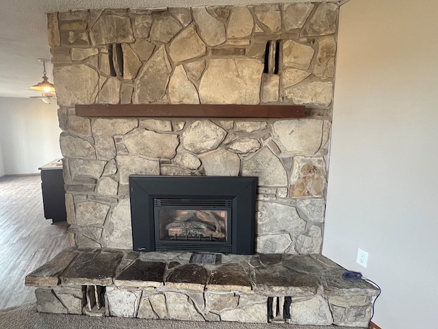 interior details featuring wood finished floors and a stone fireplace