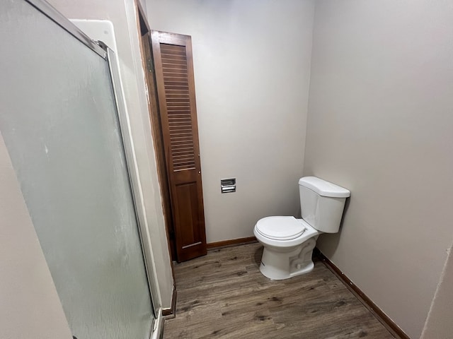 full bathroom featuring a stall shower, baseboards, toilet, and wood finished floors