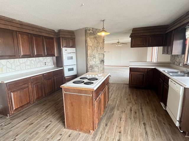 kitchen with light wood-style flooring, decorative backsplash, a sink, ceiling fan, and white appliances