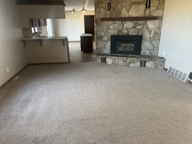 unfurnished living room with baseboards, visible vents, ceiling fan, carpet flooring, and a fireplace