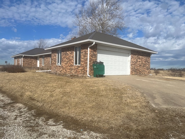 view of side of property featuring a garage, concrete driveway, and brick siding