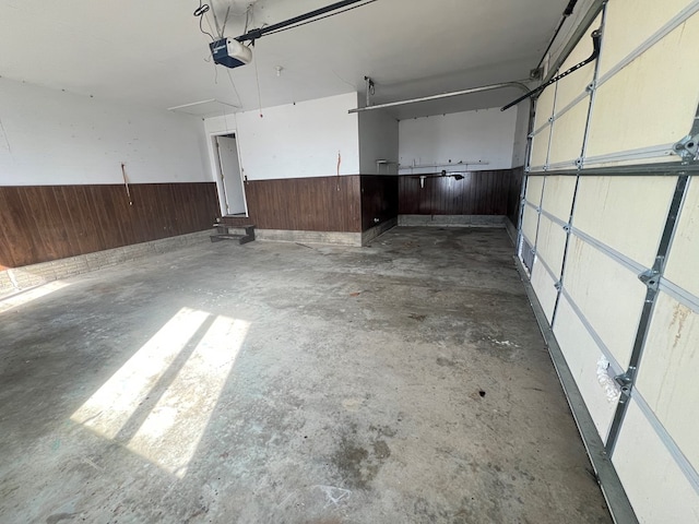 garage featuring wooden walls, wainscoting, and a garage door opener