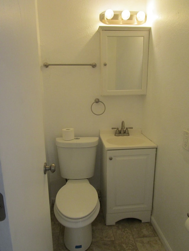 bathroom featuring toilet, vanity, and baseboards