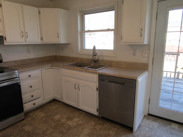 kitchen featuring appliances with stainless steel finishes, light countertops, white cabinetry, and a sink