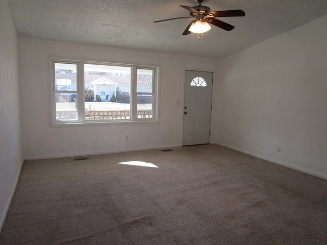 entryway with light carpet, baseboards, visible vents, and a textured ceiling