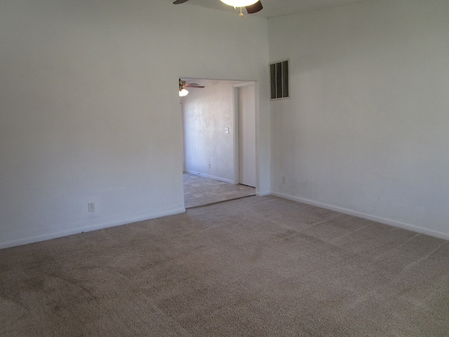 carpeted spare room featuring a ceiling fan, visible vents, and baseboards