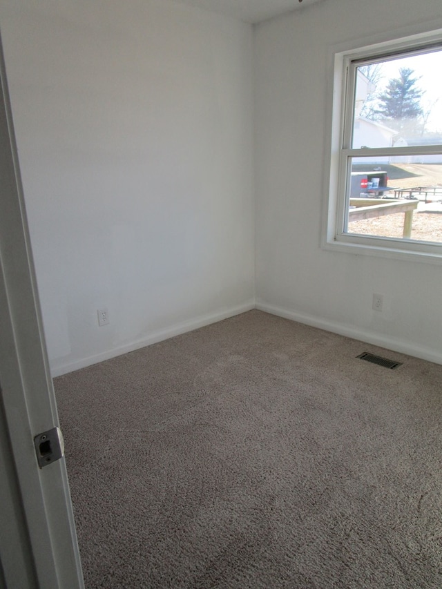 spare room with carpet, visible vents, and baseboards