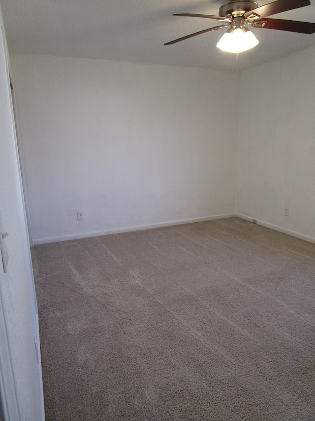 carpeted empty room featuring a ceiling fan and baseboards