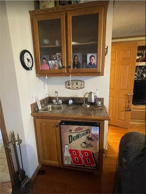 bar featuring wet bar, baseboards, dark wood-type flooring, and a sink