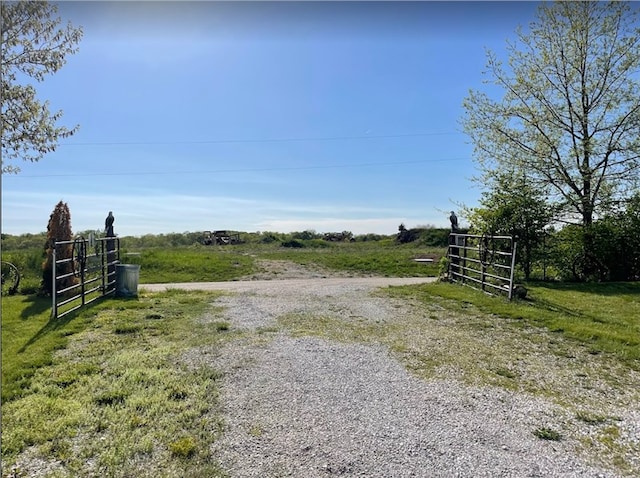 view of yard featuring a gate, a rural view, fence, and gravel driveway