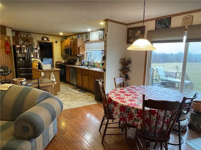 dining space with plenty of natural light, crown molding, and light wood finished floors