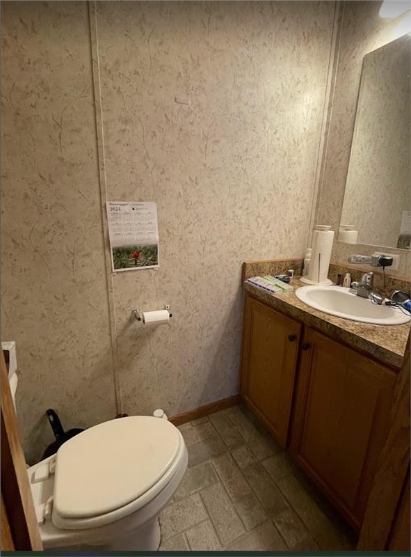 bathroom featuring toilet, baseboards, and vanity