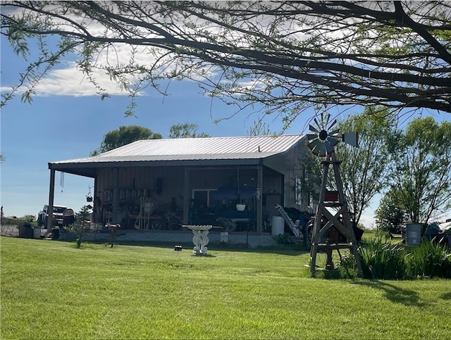 back of house with metal roof and a yard