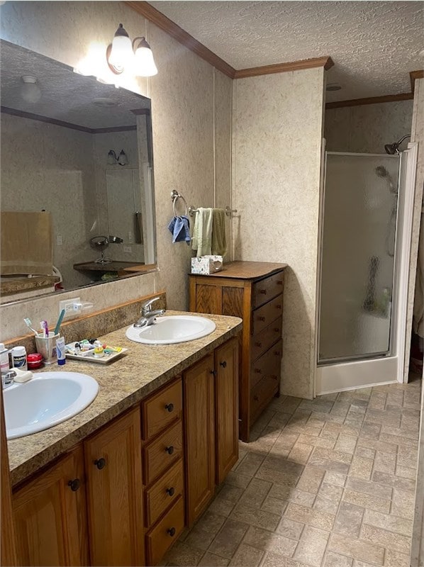 full bath with a shower stall, a textured ceiling, ornamental molding, and a sink