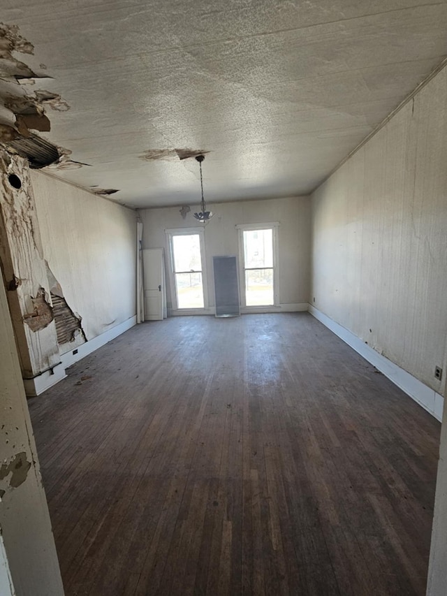 spare room with dark wood-style floors, baseboards, a textured ceiling, and an inviting chandelier