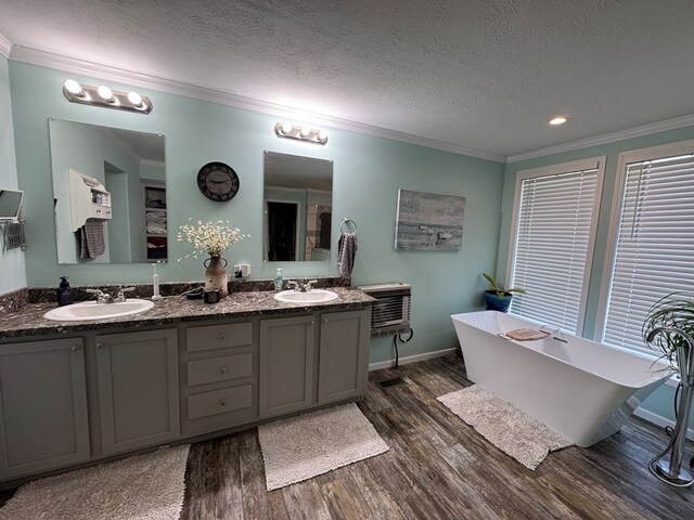 210 N Grant St, Green City, MO 63545 - full bathroom with wood finished floors, ornamental molding, double vanity, a soaking tub, and a textured ceiling