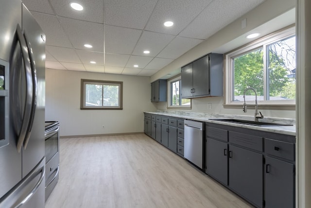 516 Barrow St, Moberly, MO 65270 - kitchen with appliances with stainless steel finishes, a sink, light wood-type flooring, light countertops, and gray cabinetry