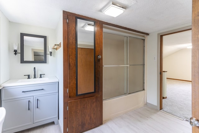 516 Barrow St, Moberly, MO 65270 - full bath featuring combined bath / shower with glass door, wood finished floors, vanity, and a textured ceiling