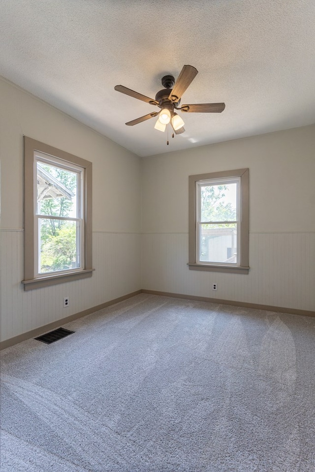 516 Barrow St, Moberly, MO 65270 - spare room with wainscoting, a textured ceiling, carpet, and ceiling fan