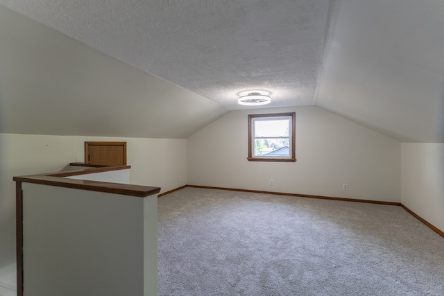 516 Barrow St, Moberly, MO 65270 - additional living space with vaulted ceiling, light colored carpet, baseboards, and a textured ceiling