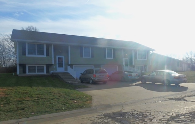 raised ranch with a garage, driveway, and a front lawn