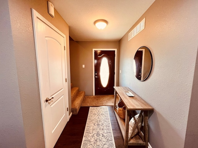 entryway featuring dark wood-type flooring and a textured ceiling