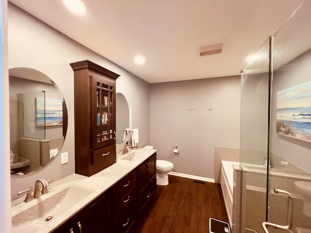 bathroom featuring a washtub, hardwood / wood-style floors, vanity, and toilet