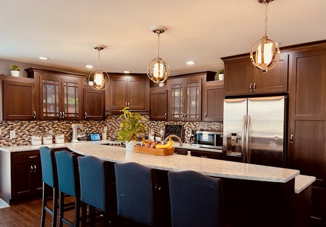 kitchen with tasteful backsplash, appliances with stainless steel finishes, a kitchen breakfast bar, and hanging light fixtures