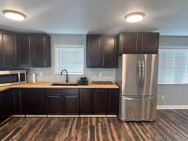 kitchen with dark wood-type flooring, dark brown cabinetry, sink, and stainless steel appliances