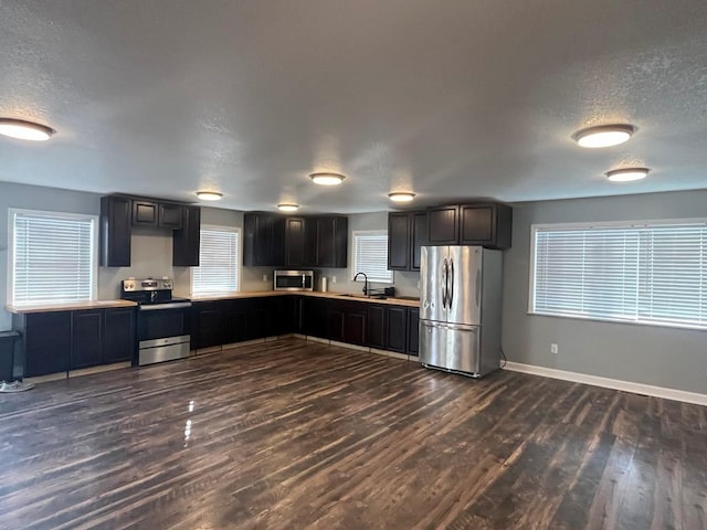 kitchen featuring sink, dark wood-type flooring, a textured ceiling, and appliances with stainless steel finishes