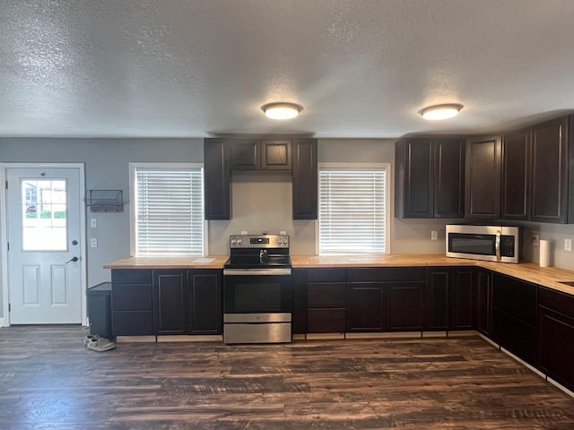 kitchen featuring a textured ceiling, dark brown cabinetry, dark wood-type flooring, and appliances with stainless steel finishes