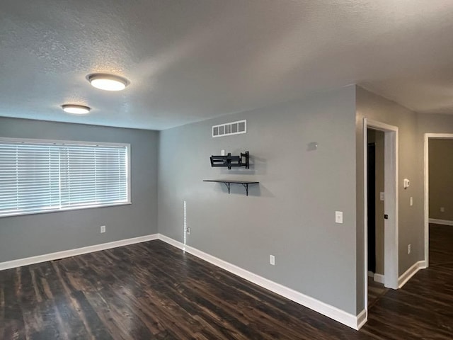 spare room featuring a textured ceiling and dark wood-type flooring