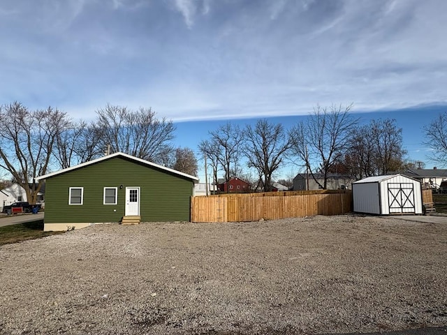 view of yard featuring an outdoor structure, a shed, fence, and entry steps