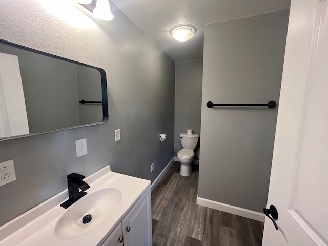 bathroom featuring hardwood / wood-style flooring, vanity, toilet, and a textured ceiling