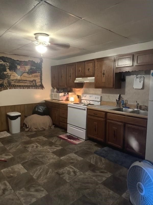 kitchen featuring wood walls, white appliances, a paneled ceiling, and sink