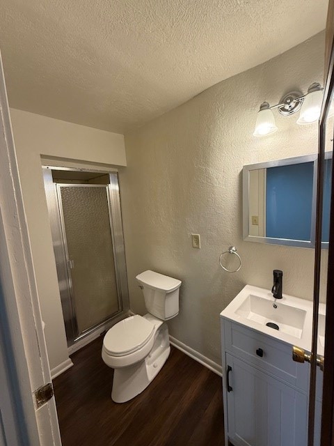 bathroom with vanity, hardwood / wood-style flooring, toilet, a textured ceiling, and walk in shower