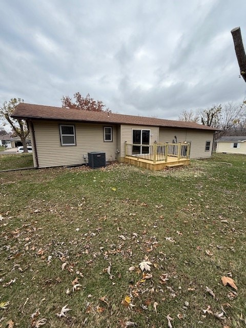 rear view of property with central AC unit, a deck, and a yard