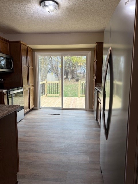 interior space featuring light wood-type flooring, appliances with stainless steel finishes, and a textured ceiling