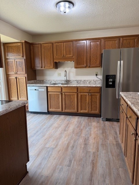 kitchen with a textured ceiling, light hardwood / wood-style floors, sink, and appliances with stainless steel finishes