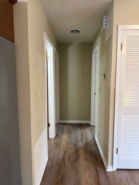 hall with dark hardwood / wood-style flooring and a textured ceiling