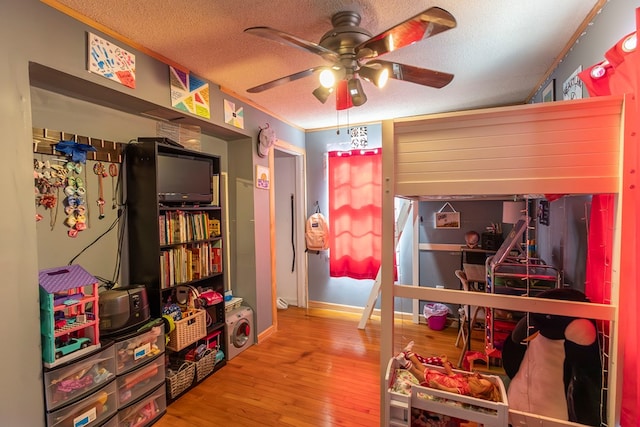 playroom featuring ceiling fan, hardwood / wood-style flooring, ornamental molding, and a textured ceiling