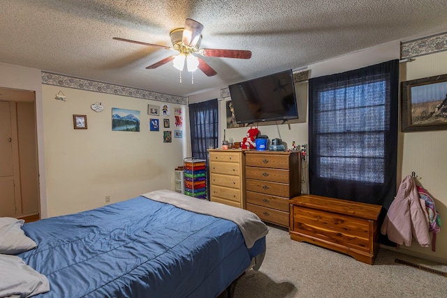 bedroom with ceiling fan, carpet flooring, and a textured ceiling